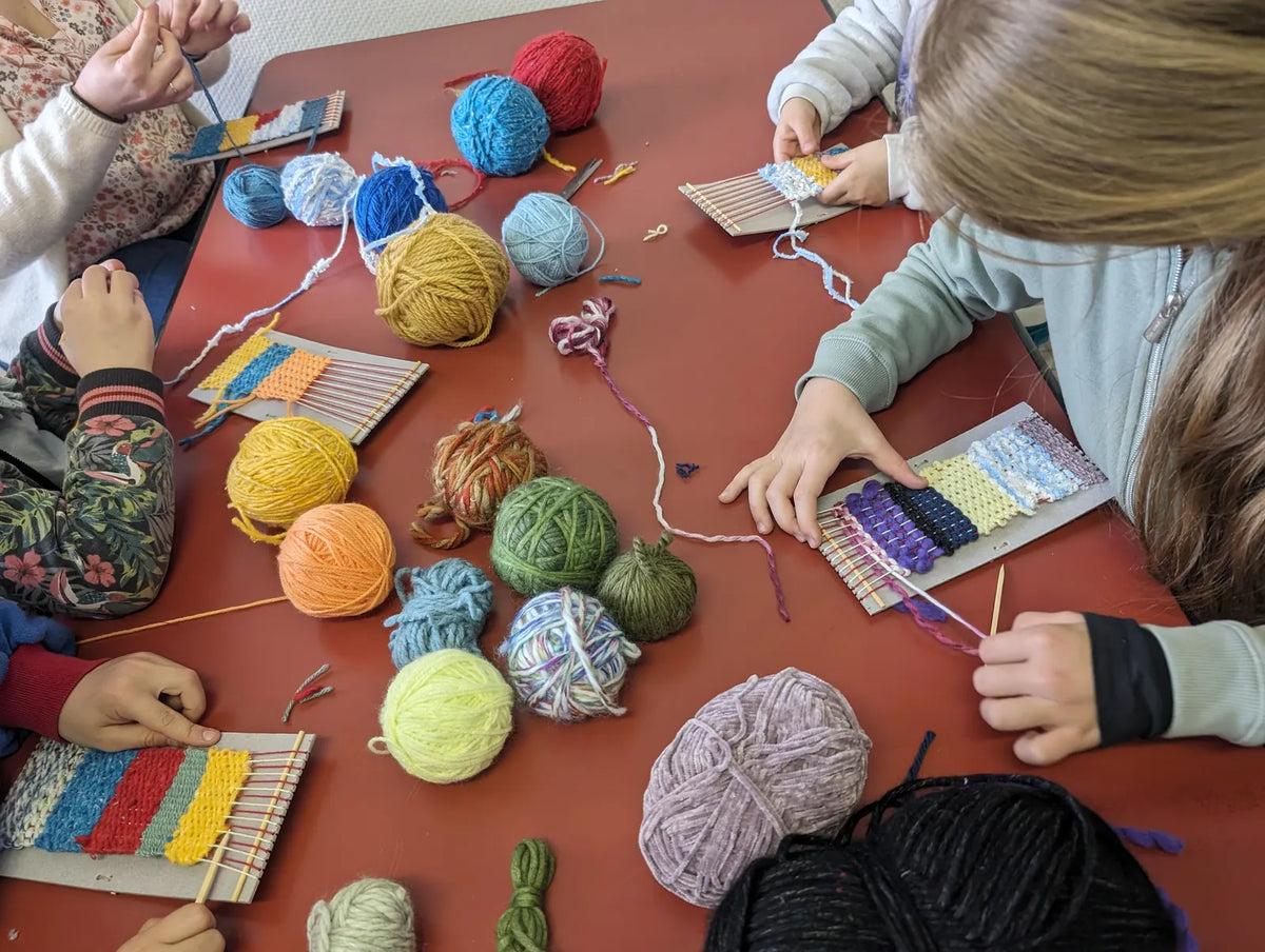 Atelier découverte du tissage : enfants tissant sur de petits métiers avec des pelotes de laine colorées, Atelier La Trame (Cantal)