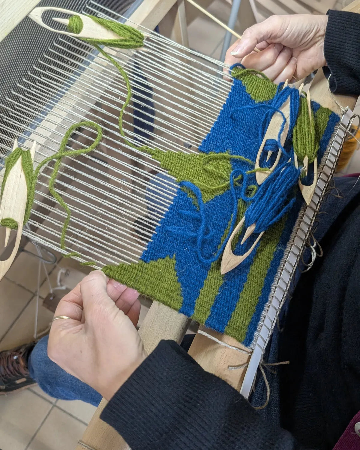 Stage kilim : tapisserie bleue et verte en cours de tissage avec papillons de laine sur métier vertical
